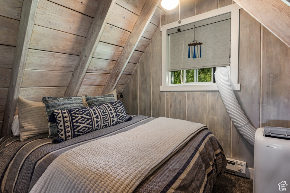 Bedroom with lofted ceiling, carpet flooring, baseboard heating, and wood walls