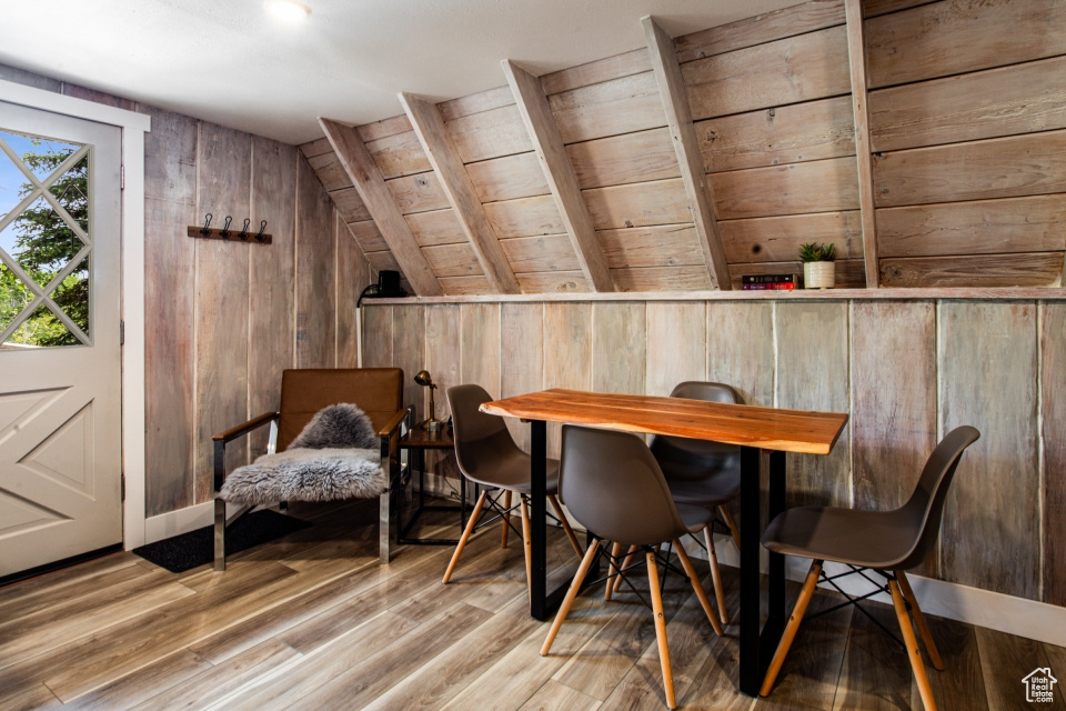 Living area with lofted ceiling, wooden walls, and light hardwood / wood-style flooring
