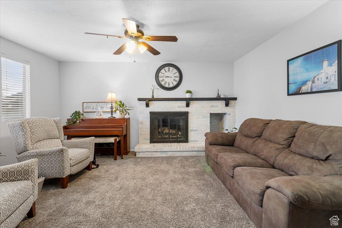 Carpeted living room with ceiling fan and a fireplace