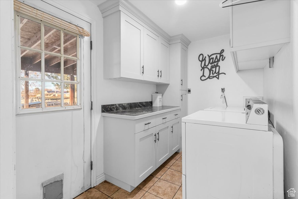 Washroom featuring washer and dryer, cabinets, and light tile patterned flooring