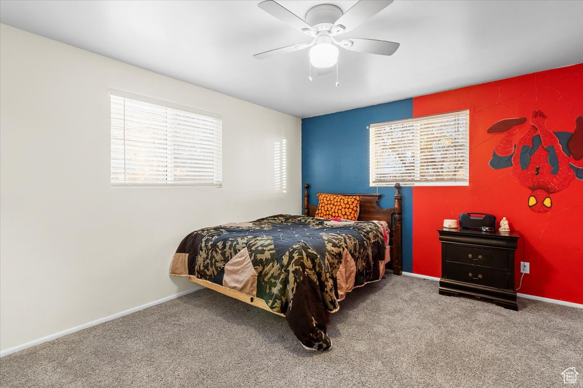 Bedroom with a big walk-in closet, ceiling fan, and carpet flooring