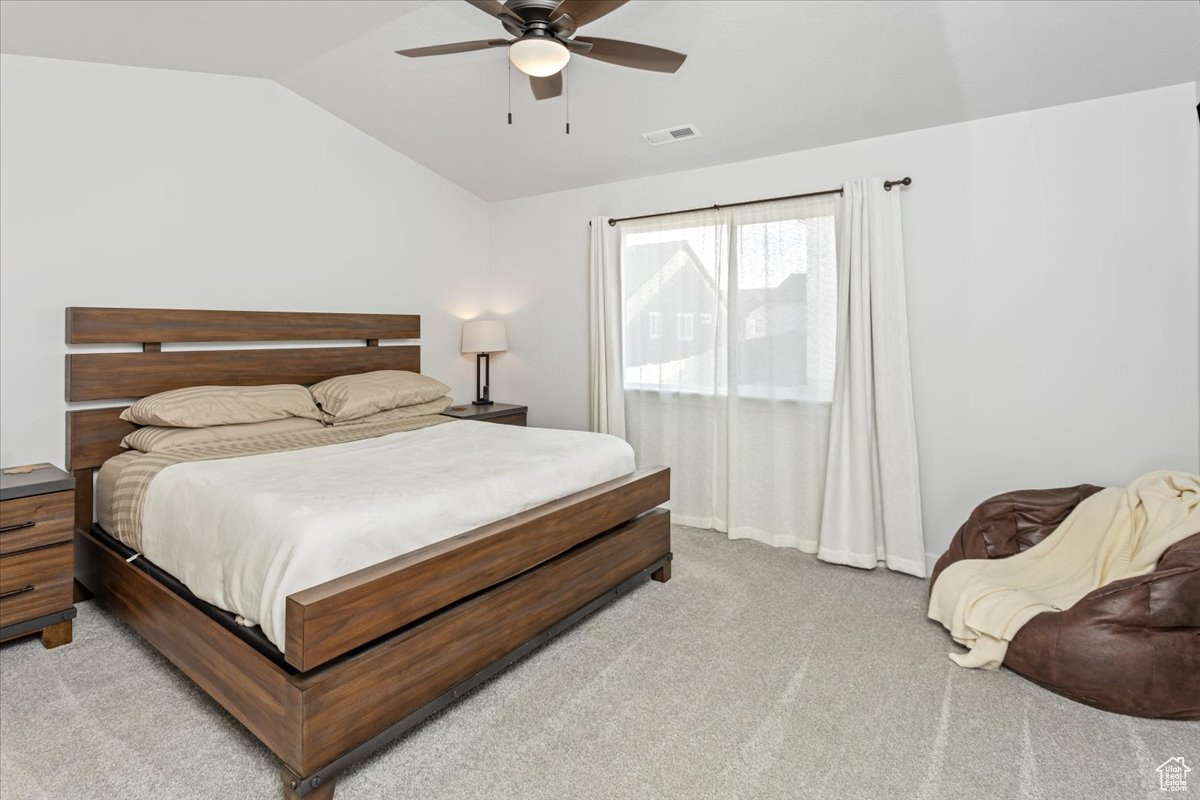 Carpeted bedroom with vaulted ceiling and ceiling fan
