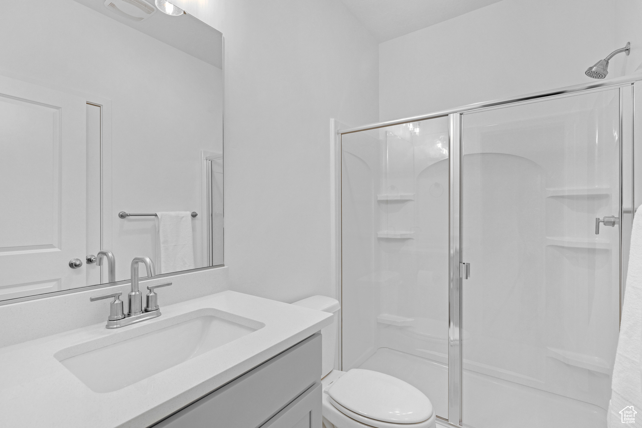 Bathroom featuring vanity, a shower with shower door, and toilet