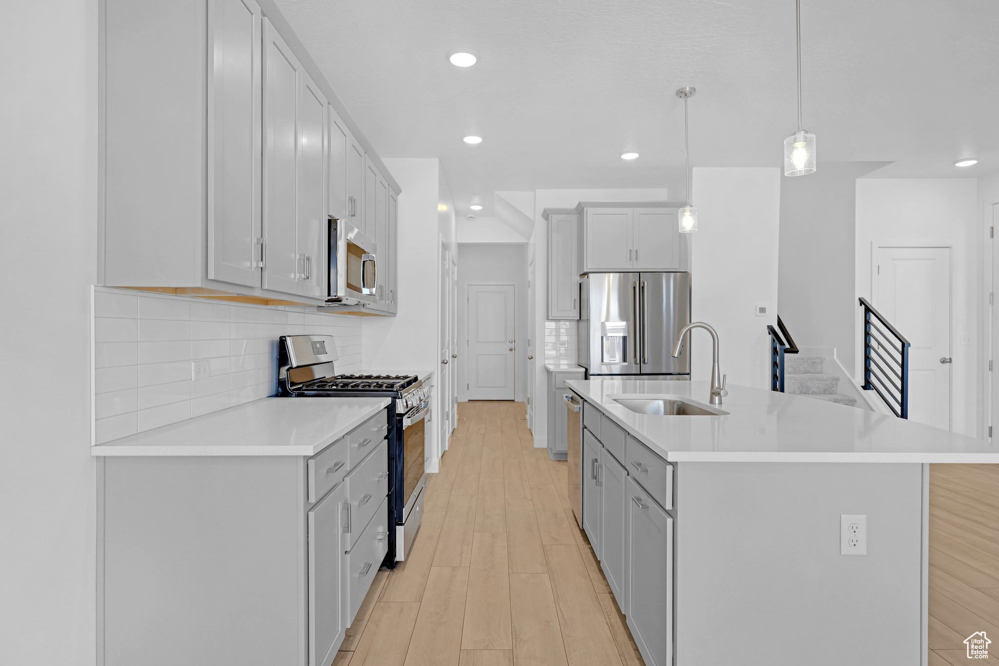 Kitchen with sink, tasteful backsplash, decorative light fixtures, a center island with sink, and stainless steel appliances