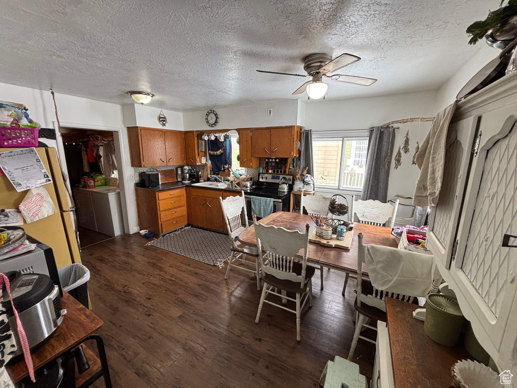 Dining area featuring sink, a textured ceiling, dark hardwood / wood-style floors, ceiling fan, and washer / clothes dryer