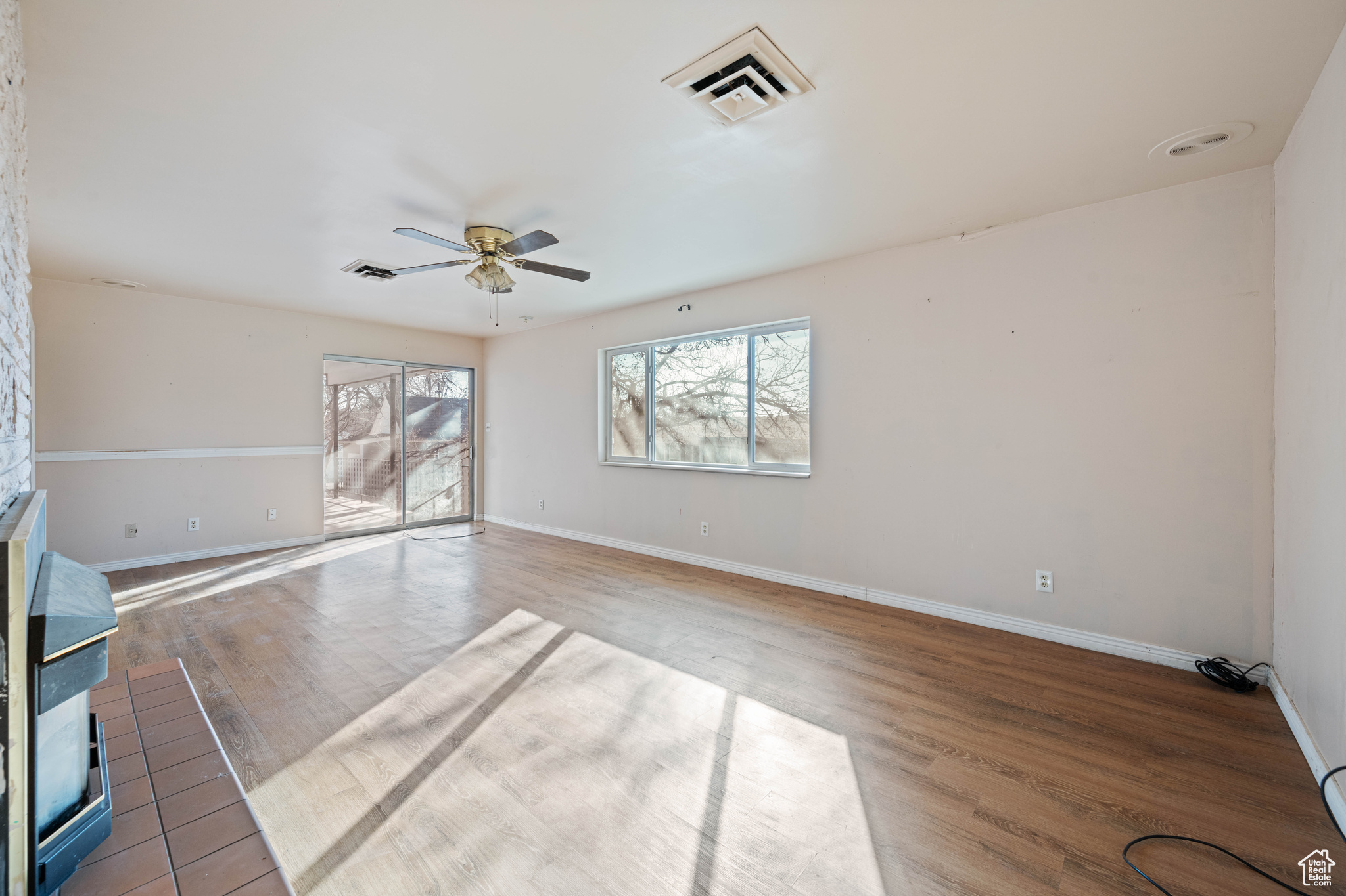 Unfurnished living room featuring ceiling fan and light hardwood / wood-style floors