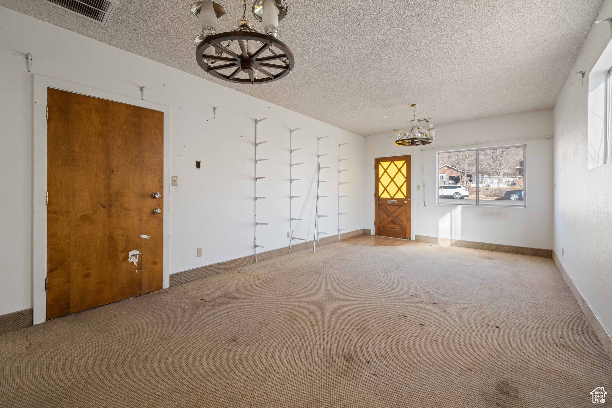 Unfurnished room featuring carpet floors, a textured ceiling, and a chandelier