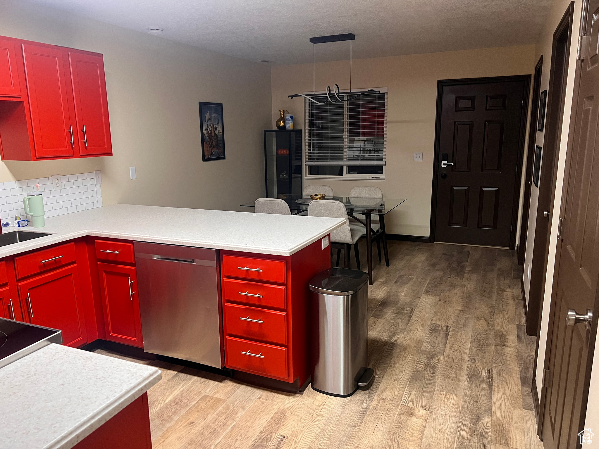 Kitchen featuring tasteful backsplash, dishwasher, light hardwood / wood-style floors, and kitchen peninsula