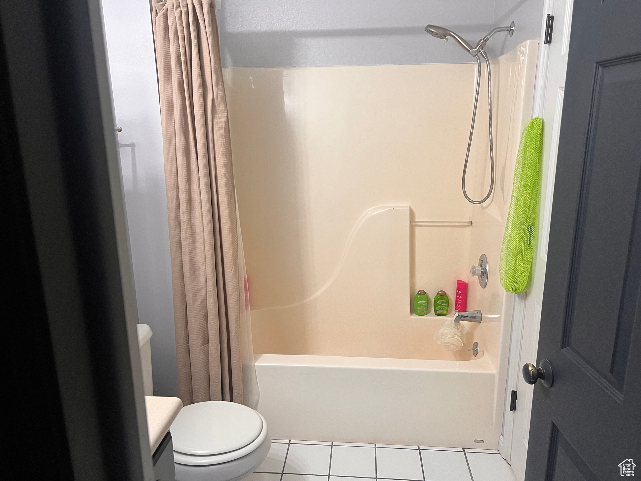 Bathroom with shower / tub combo with curtain, toilet, and tile patterned flooring