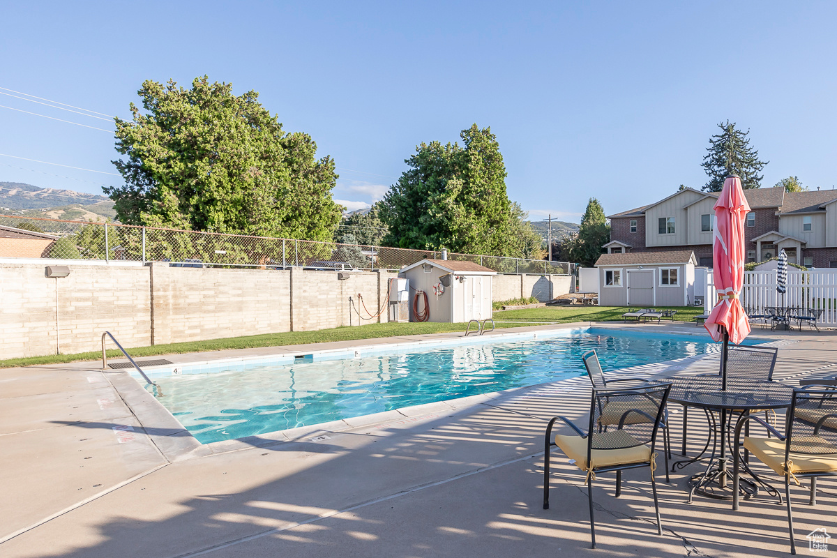 View of swimming pool with a mountain view, a patio area, and a storage shed