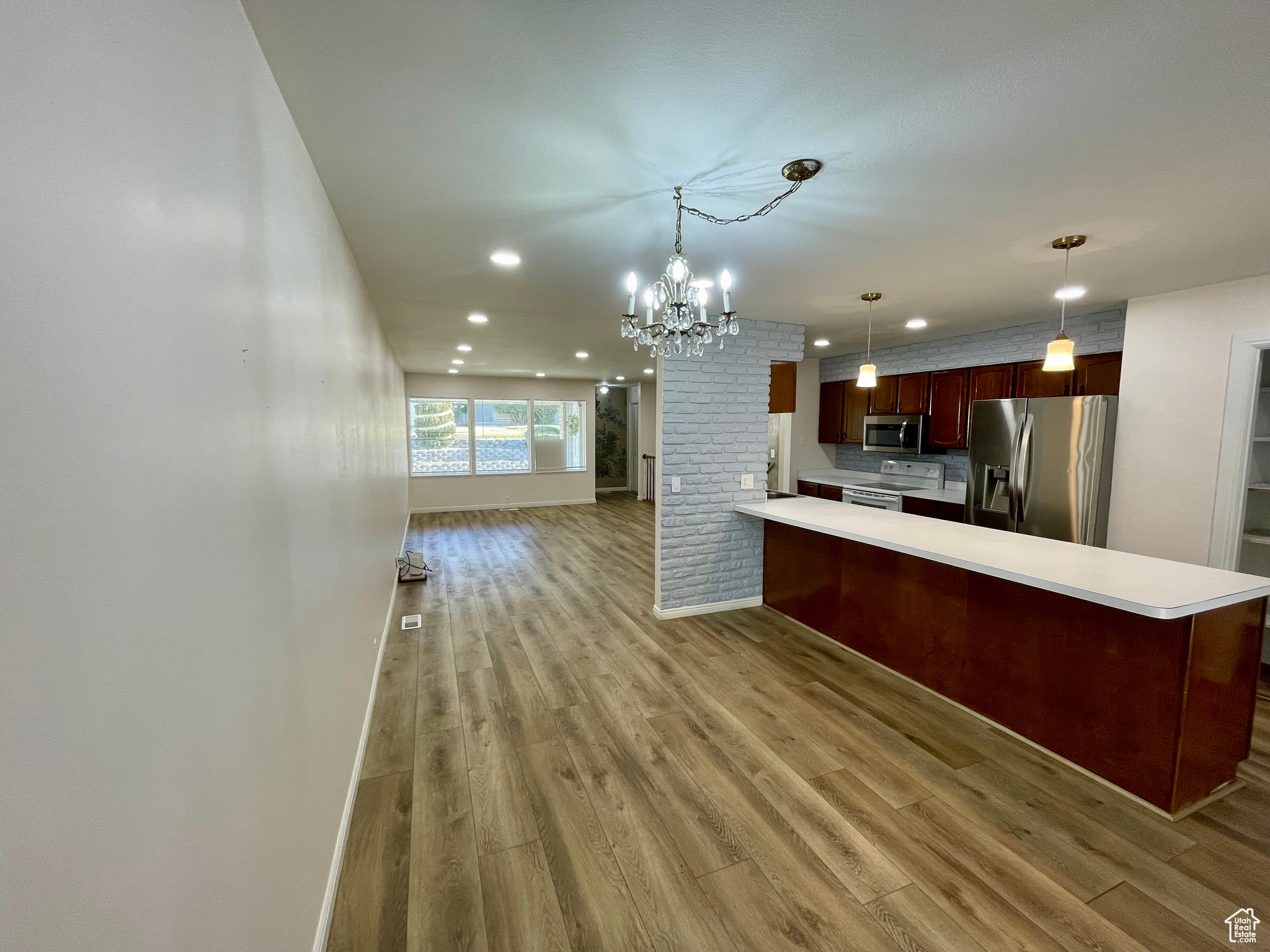 Kitchen featuring pendant lighting, tasteful backsplash, kitchen peninsula, stainless steel appliances, and light wood-type flooring