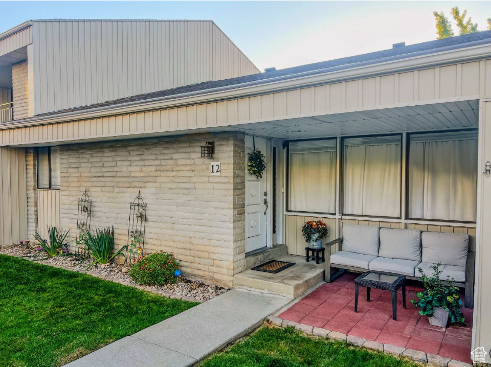 Entrance to property with a patio and a lawn