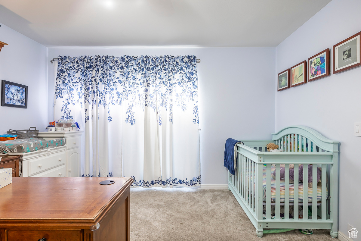 Bedroom with light carpet and a crib