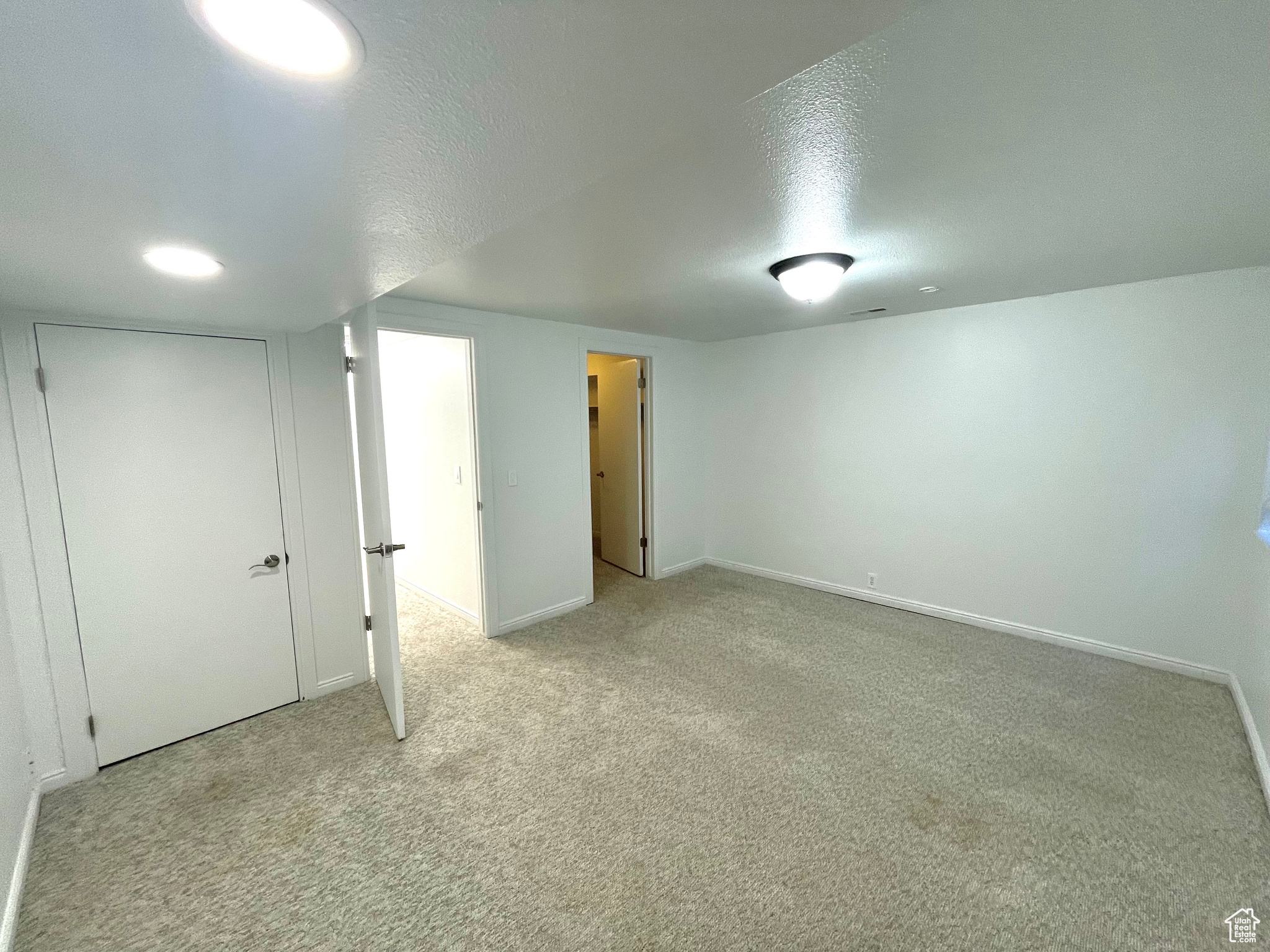 Interior space with light colored carpet and a textured ceiling