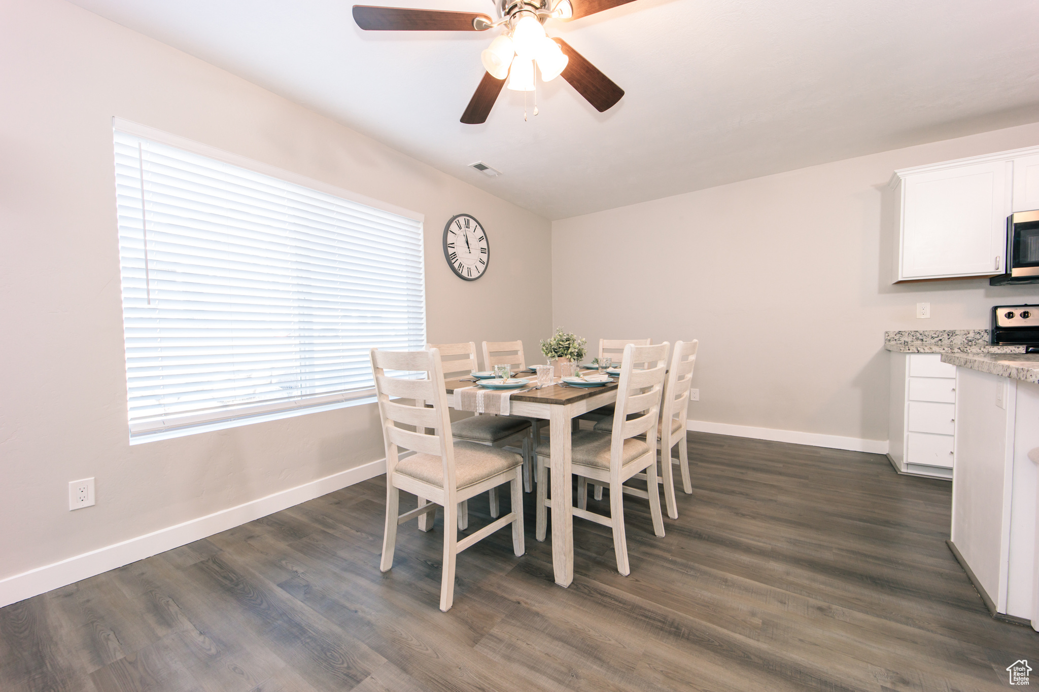 Dining area with dark wood-type flooring and ceiling fan
