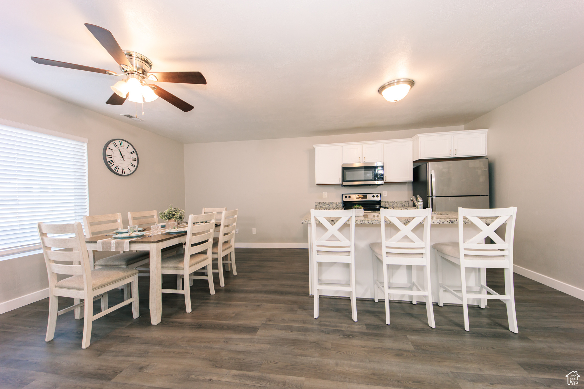 Kitchen featuring a kitchen bar, dark hardwood / wood-style floors, white cabinets, and appliances with stainless steel finishes