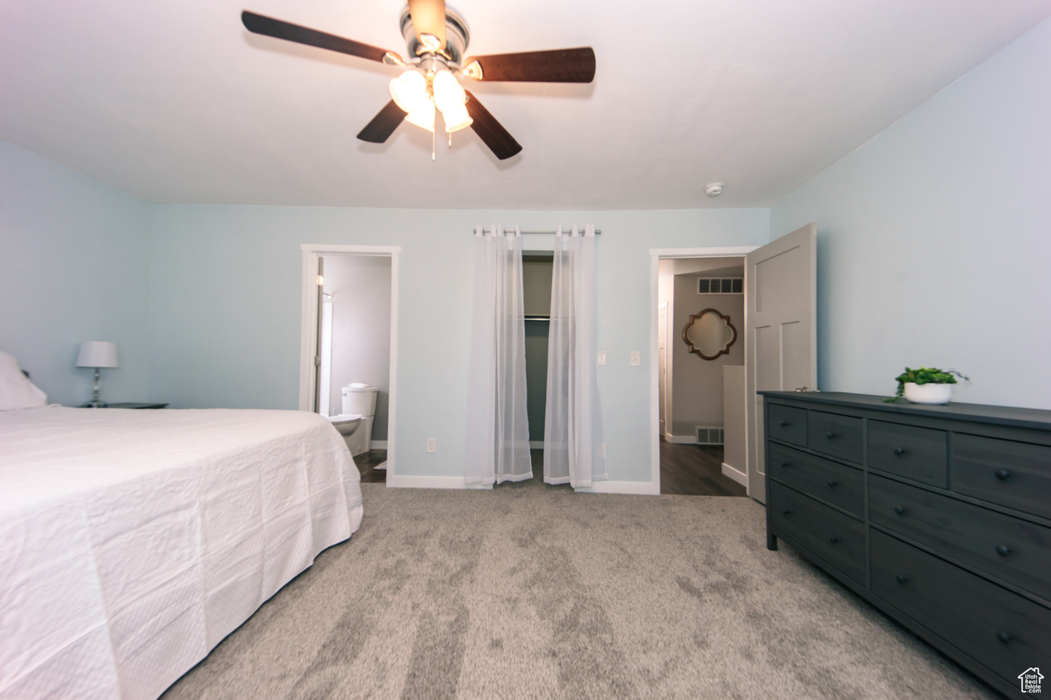 Bedroom featuring light carpet, ensuite bath, and ceiling fan