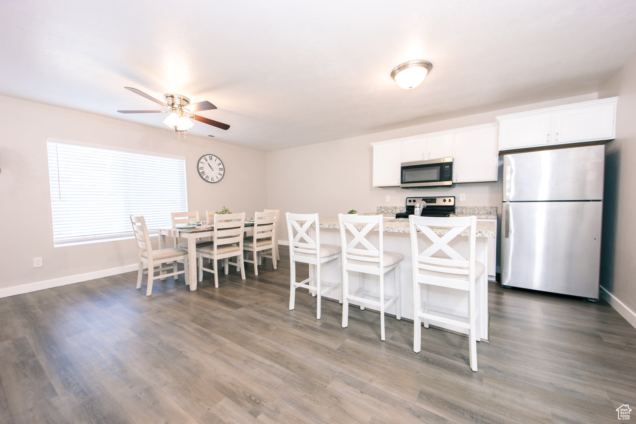 Kitchen with stainless steel appliances, light stone countertops, white cabinets, and a kitchen bar