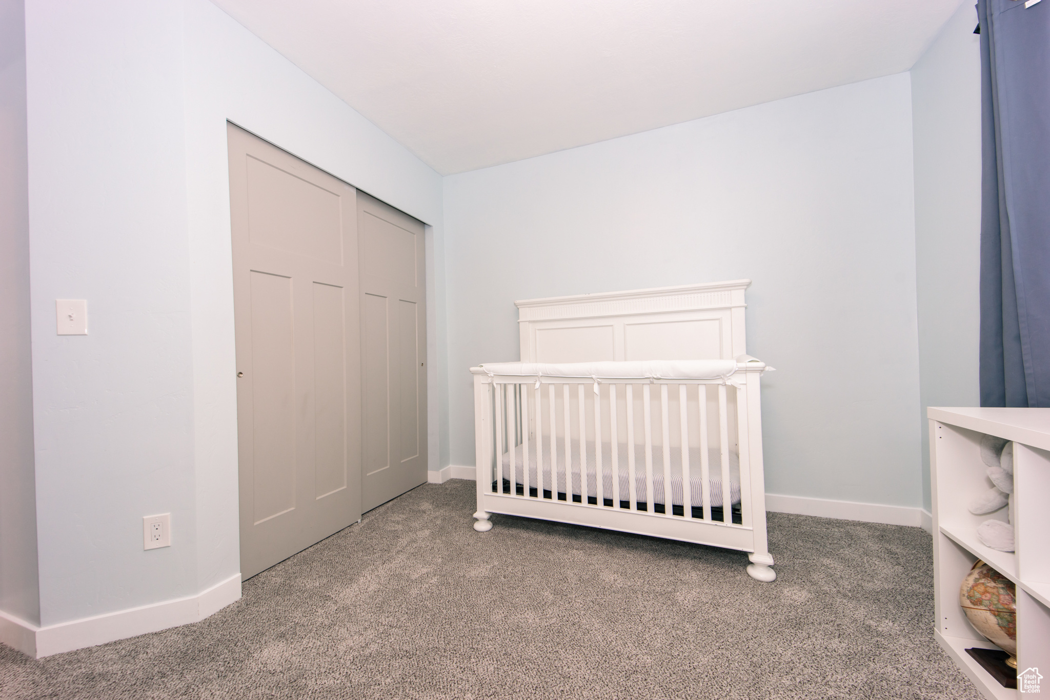 Unfurnished bedroom featuring a crib, a closet, and carpet