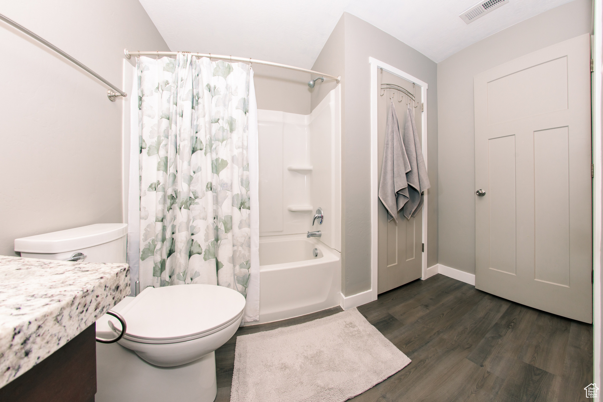 Full bathroom featuring wood-type flooring, vanity, shower / tub combo, and toilet