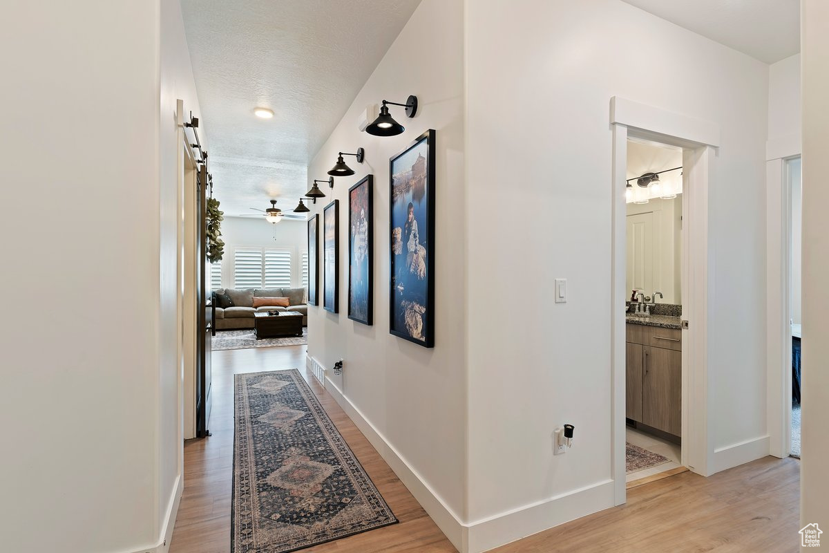Corridor featuring a barn door, sink, a textured ceiling, and light hardwood / wood-style floors