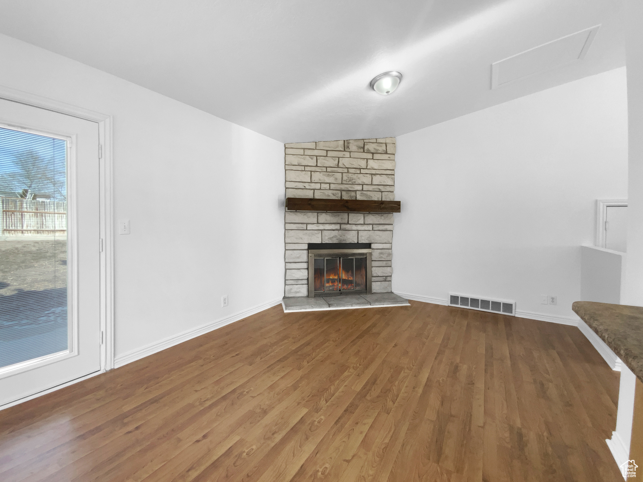 Unfurnished living room featuring hardwood / wood-style floors and a stone fireplace