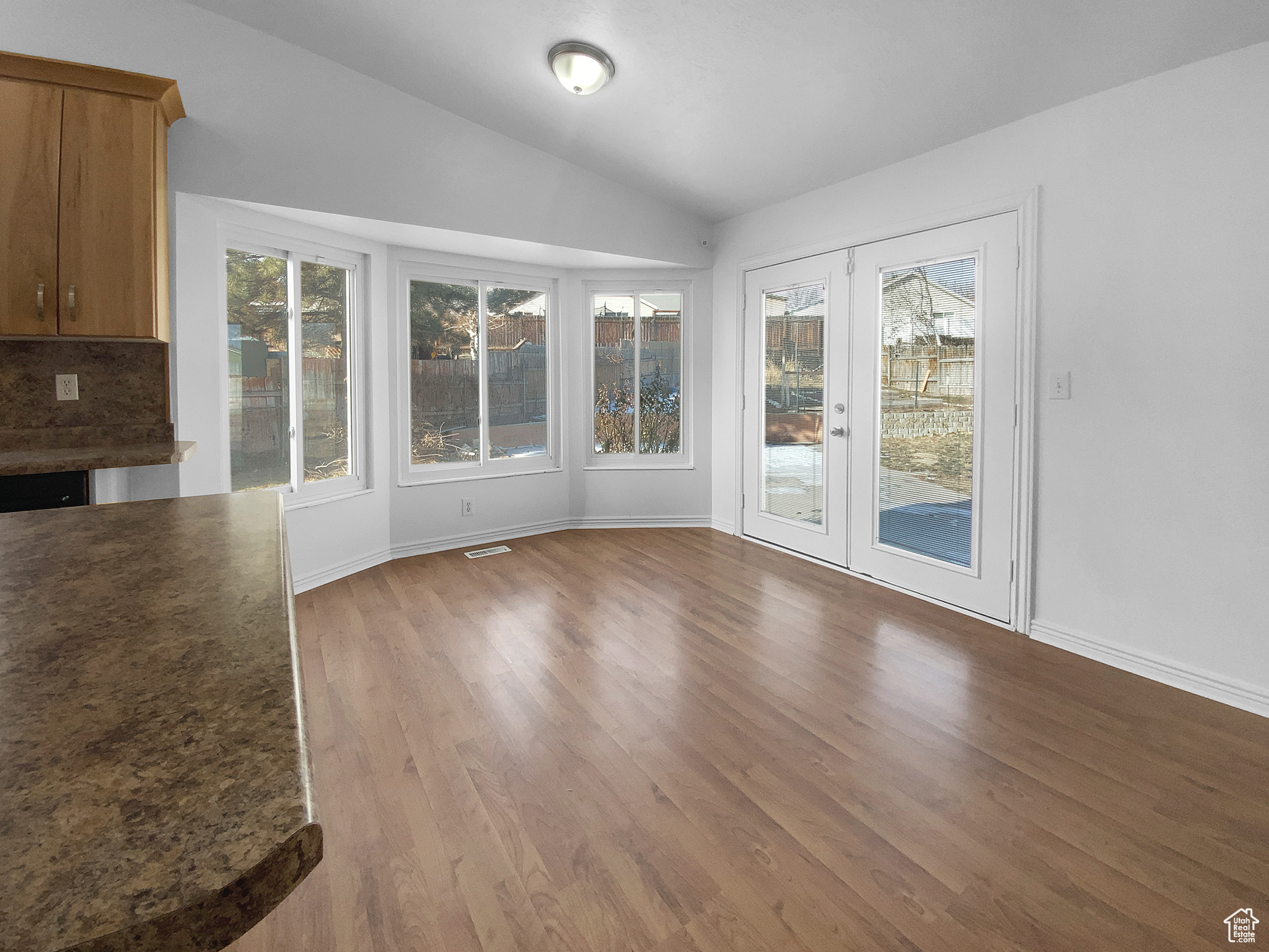Unfurnished dining area featuring lofted ceiling, hardwood / wood-style flooring, and french doors