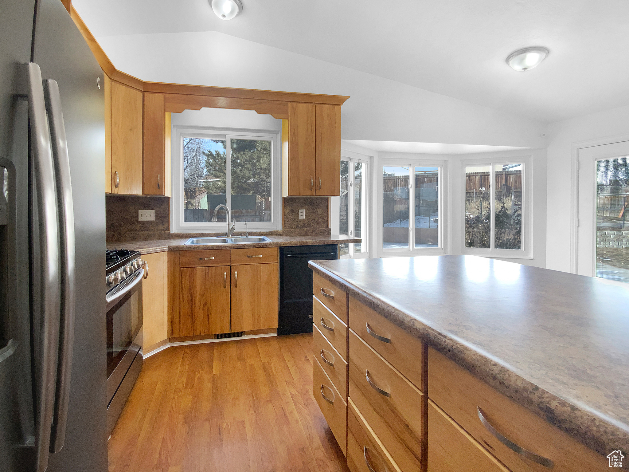 Kitchen with stainless steel appliances, sink, vaulted ceiling, and light hardwood / wood-style flooring