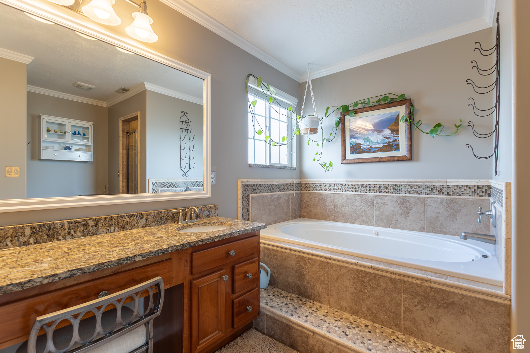 Bathroom featuring a relaxing tiled tub, vanity, and crown molding