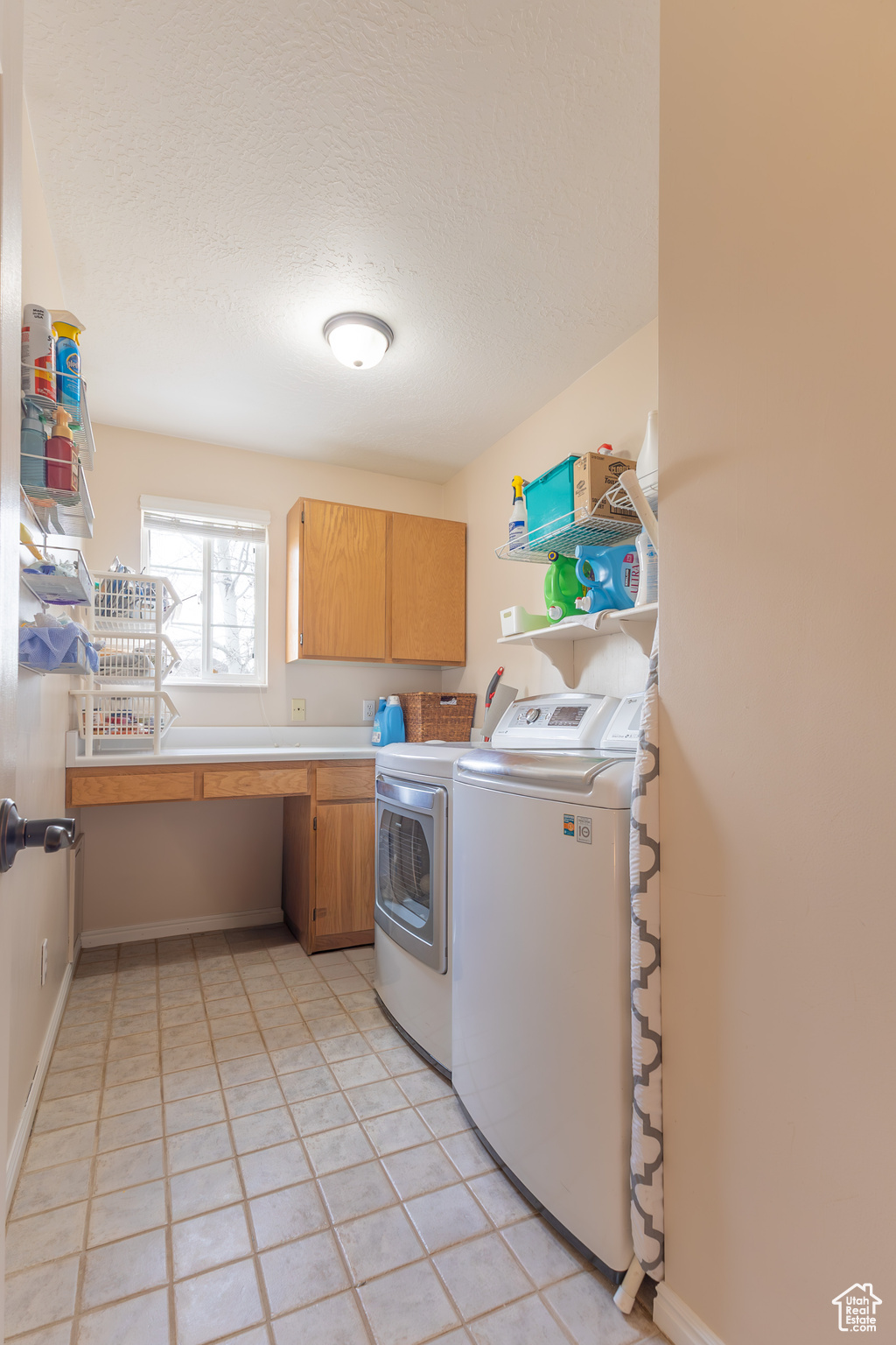 Laundry area featuring cabinets, light tile patterned floors, a textured ceiling, and independent washer and dryer