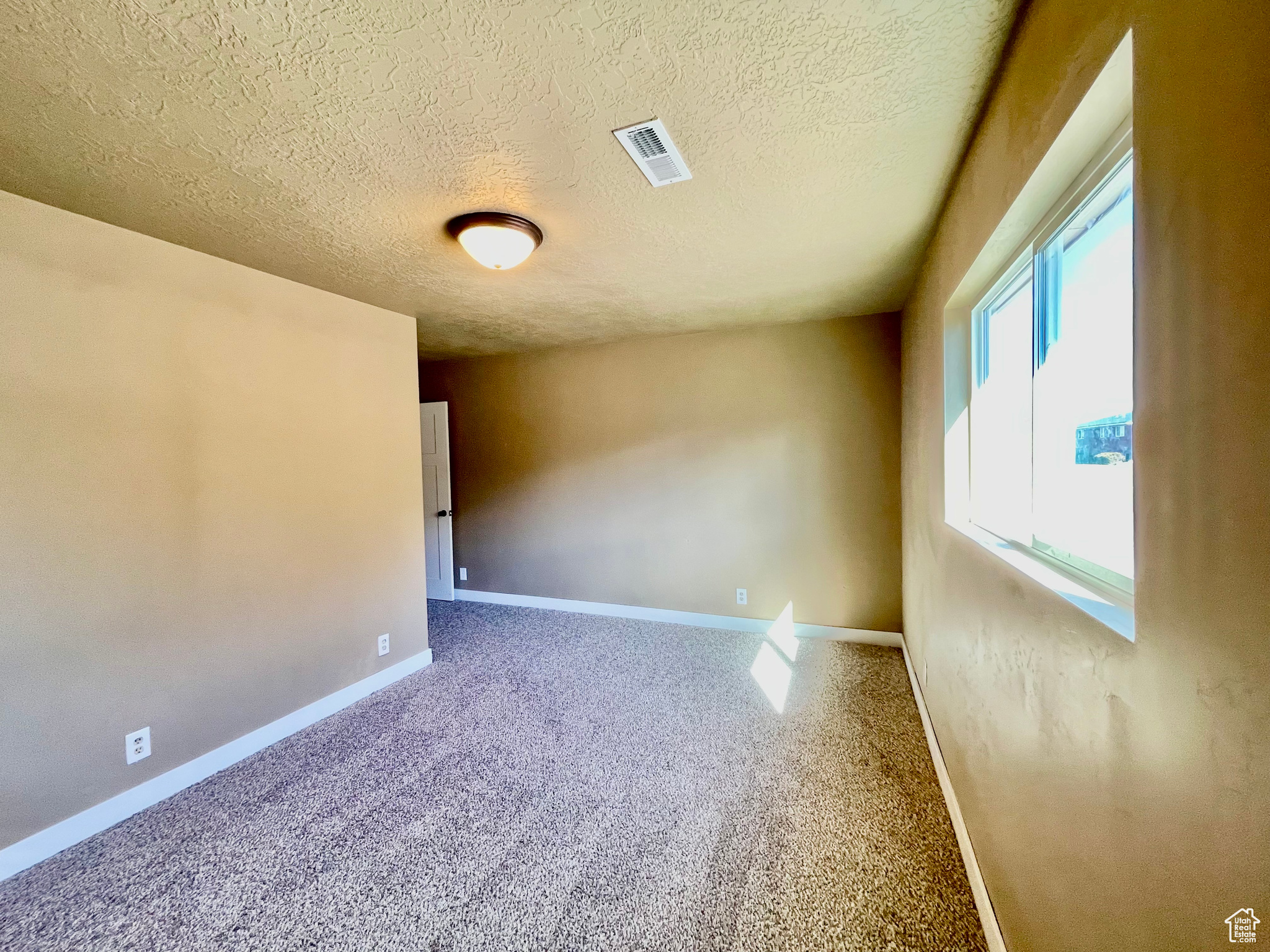 Carpeted empty room with a textured ceiling