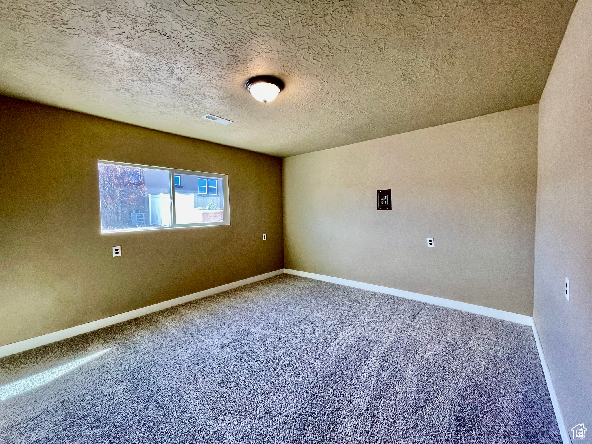 Carpeted spare room with a textured ceiling
