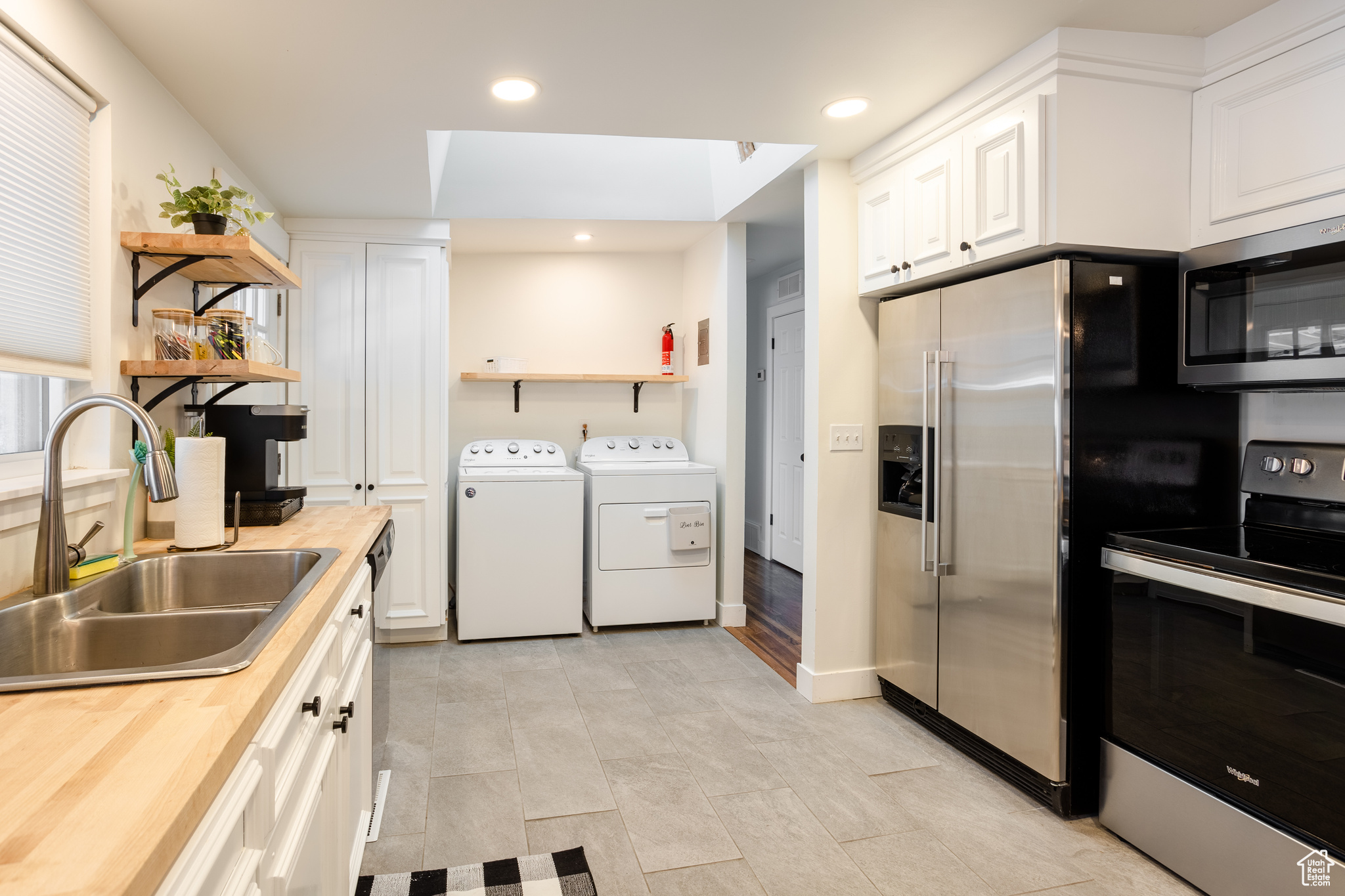 Kitchen with independent washer and dryer, stainless steel appliances, sink, and wooden counters