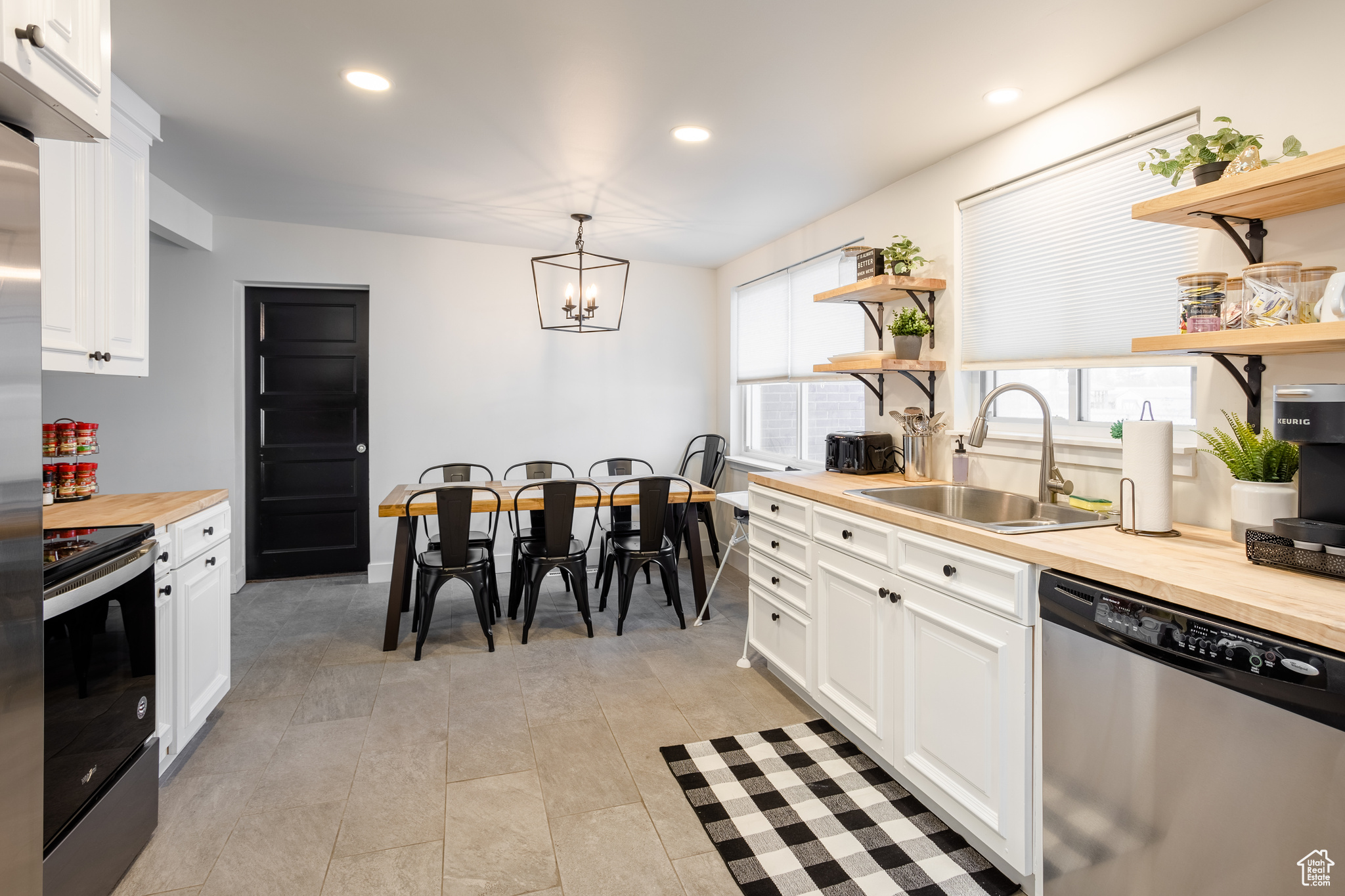 Kitchen with pendant lighting, wood counters, appliances with stainless steel finishes, and white cabinets