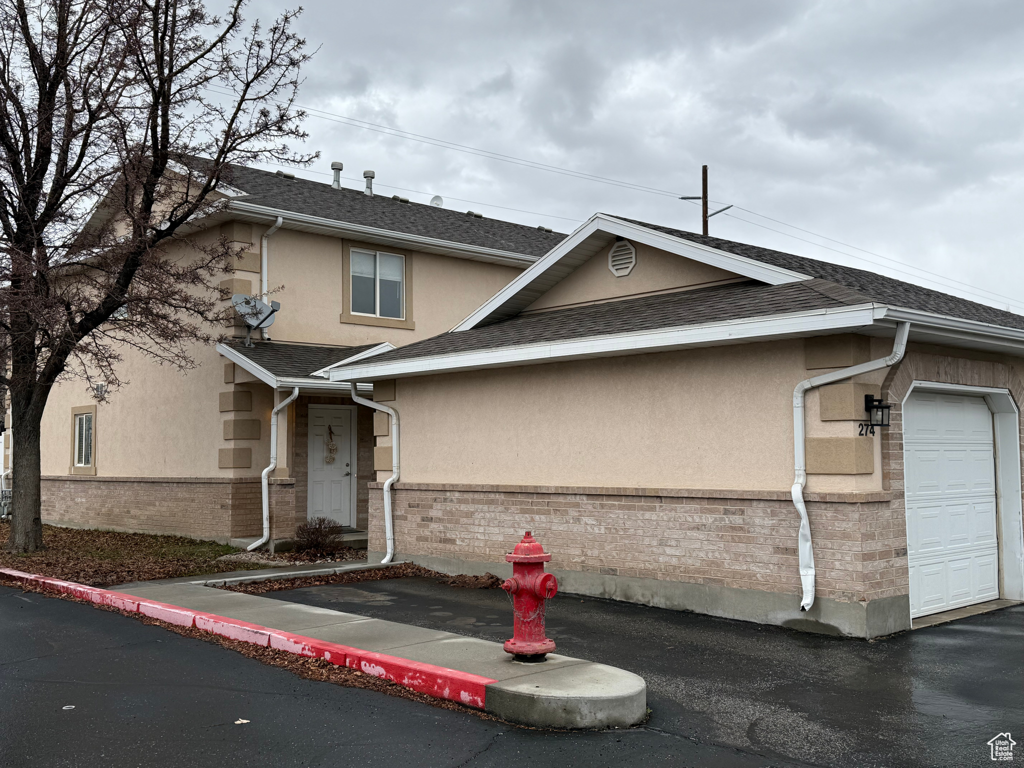 View of front of home with stucco siding, a garage, roof with shingles, and brick siding