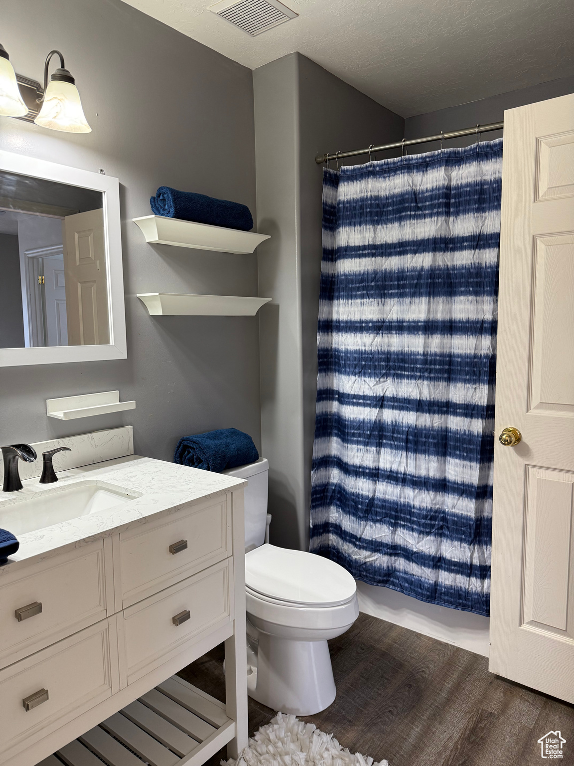 Full bathroom featuring visible vents, a shower with curtain, toilet, wood finished floors, and vanity