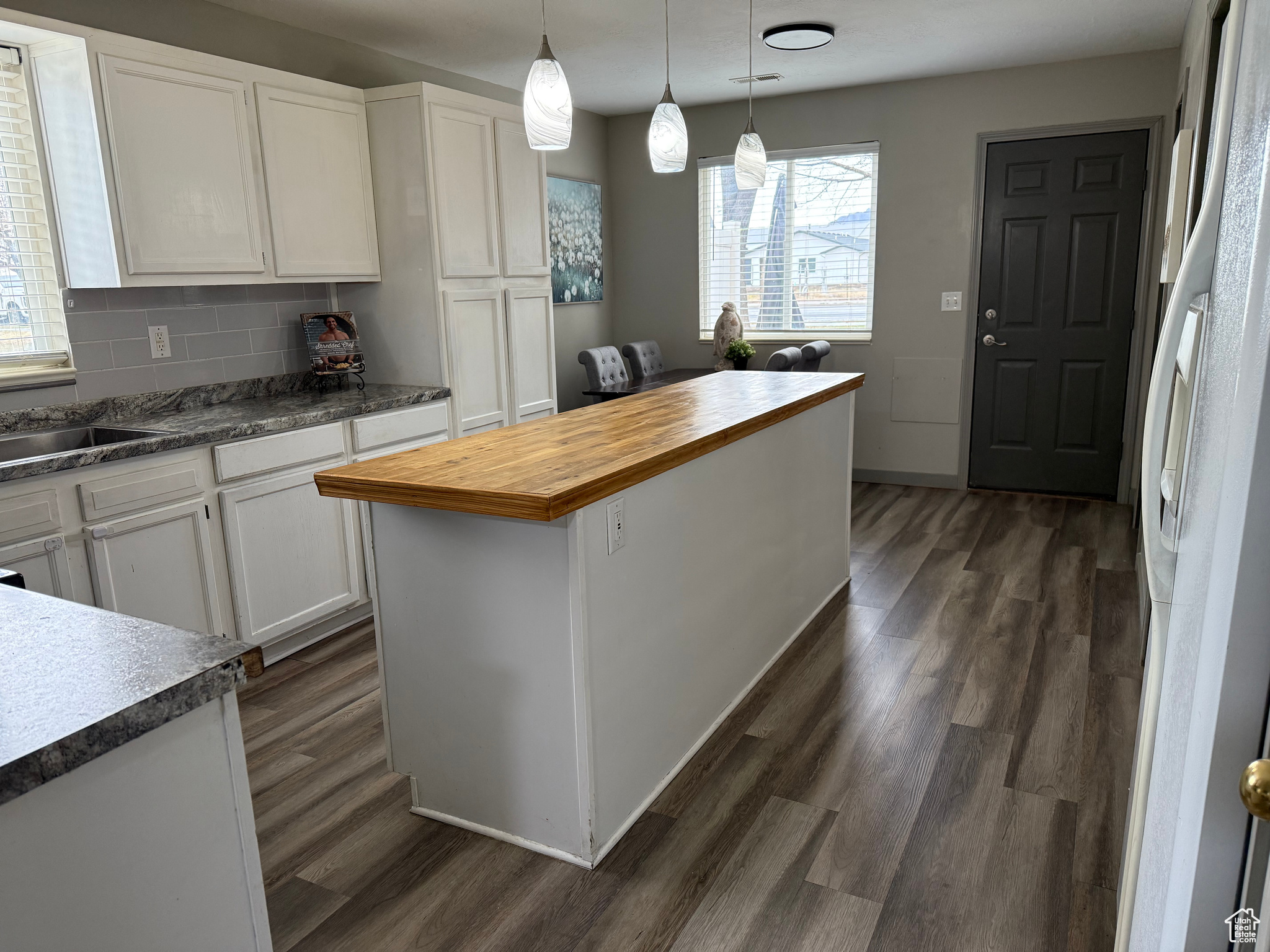 Kitchen featuring wooden counters, dark wood finished floors, freestanding refrigerator, white cabinets, and tasteful backsplash