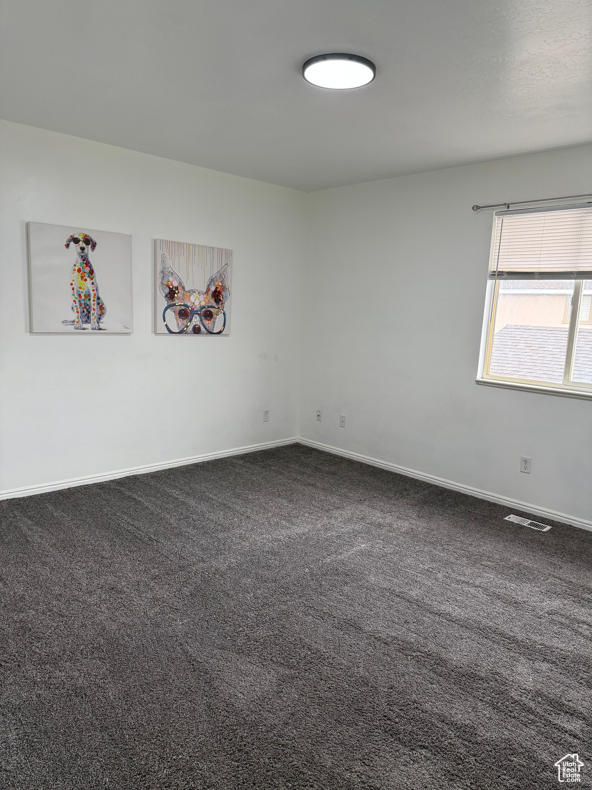 Spare room with visible vents, baseboards, and dark colored carpet