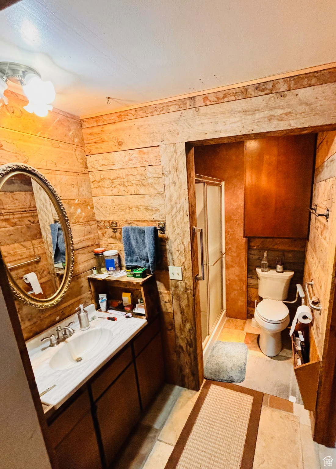 Full bathroom with wood walls, a stall shower, toilet, and vanity