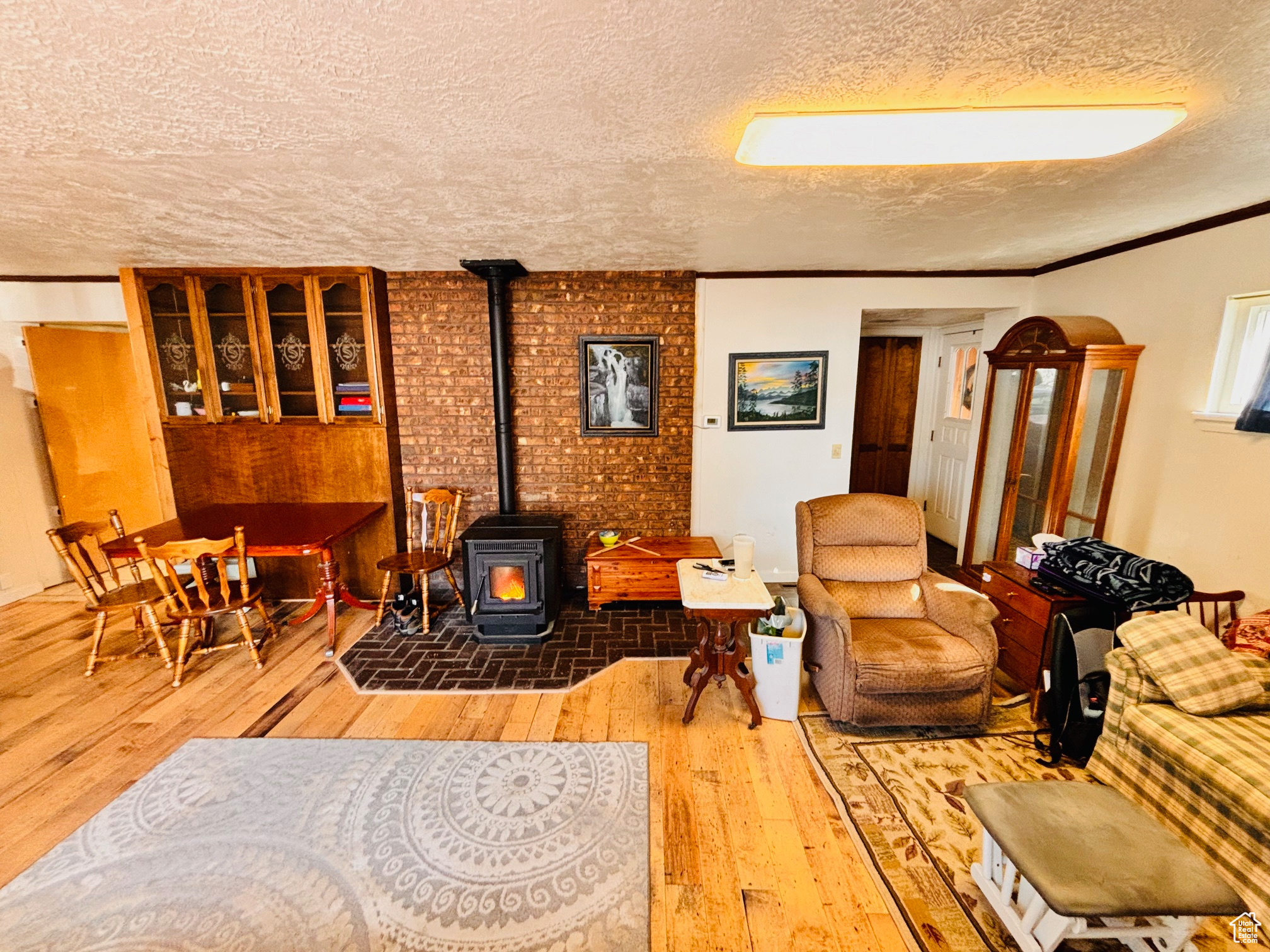 Sitting room with a textured ceiling, a wood stove, wood-type flooring, and ornamental molding