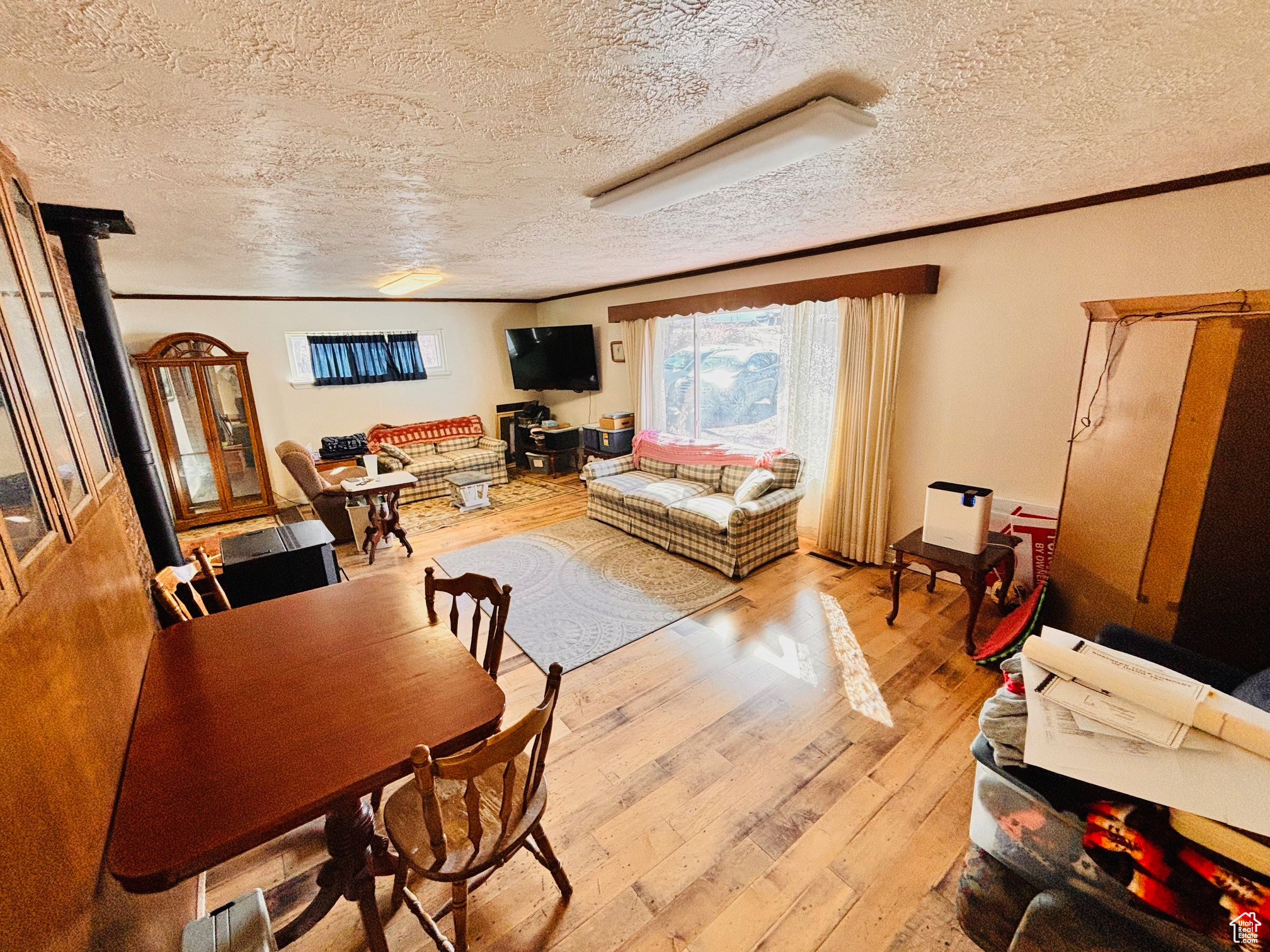 Dining space featuring a textured ceiling, light wood-style floors, and ornamental molding