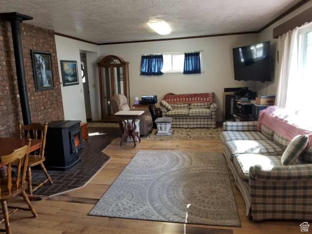 Living room featuring a wealth of natural light, ornamental molding, a wood stove, and wood finished floors