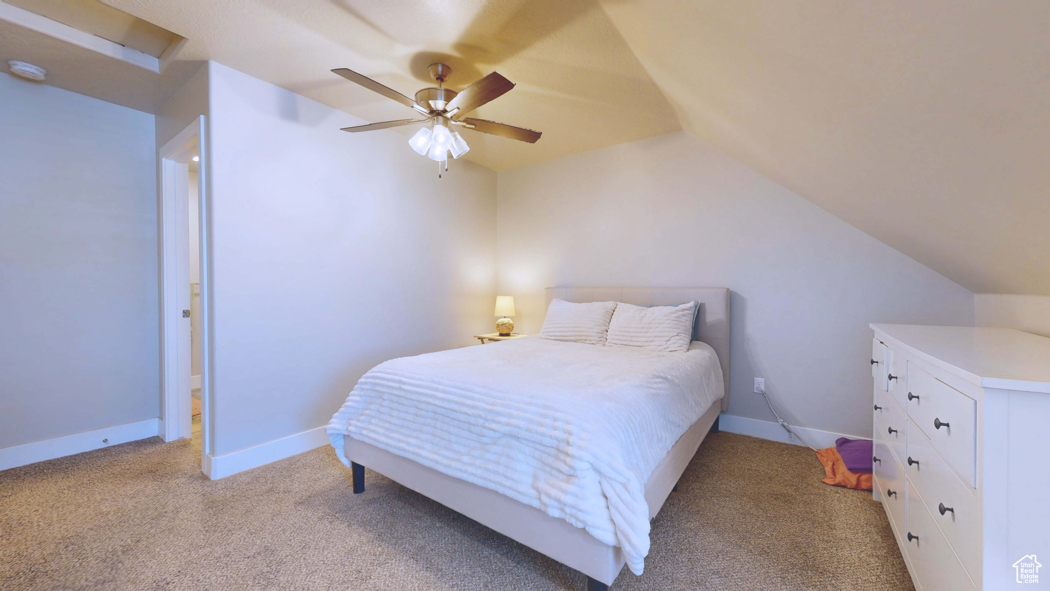 Carpeted bedroom with vaulted ceiling and ceiling fan