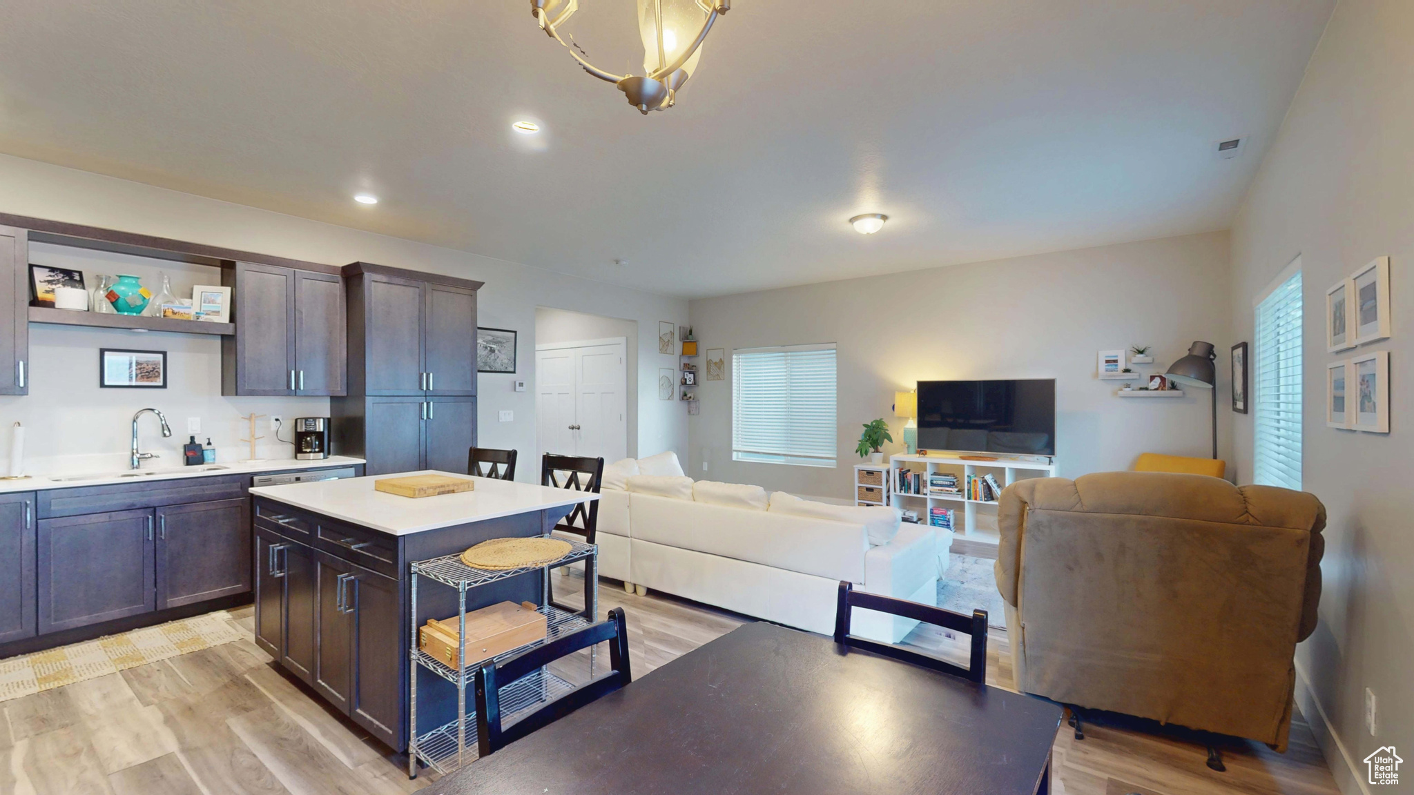 Kitchen featuring a kitchen island, sink, dark brown cabinets, and light hardwood / wood-style flooring
