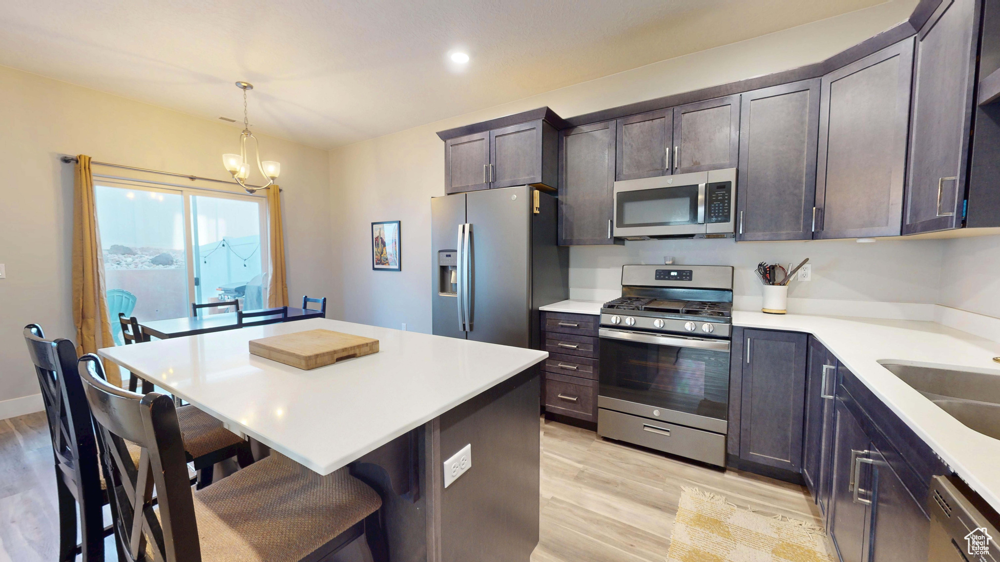 Kitchen featuring a breakfast bar area, dark brown cabinets, hanging light fixtures, a kitchen island, and stainless steel appliances