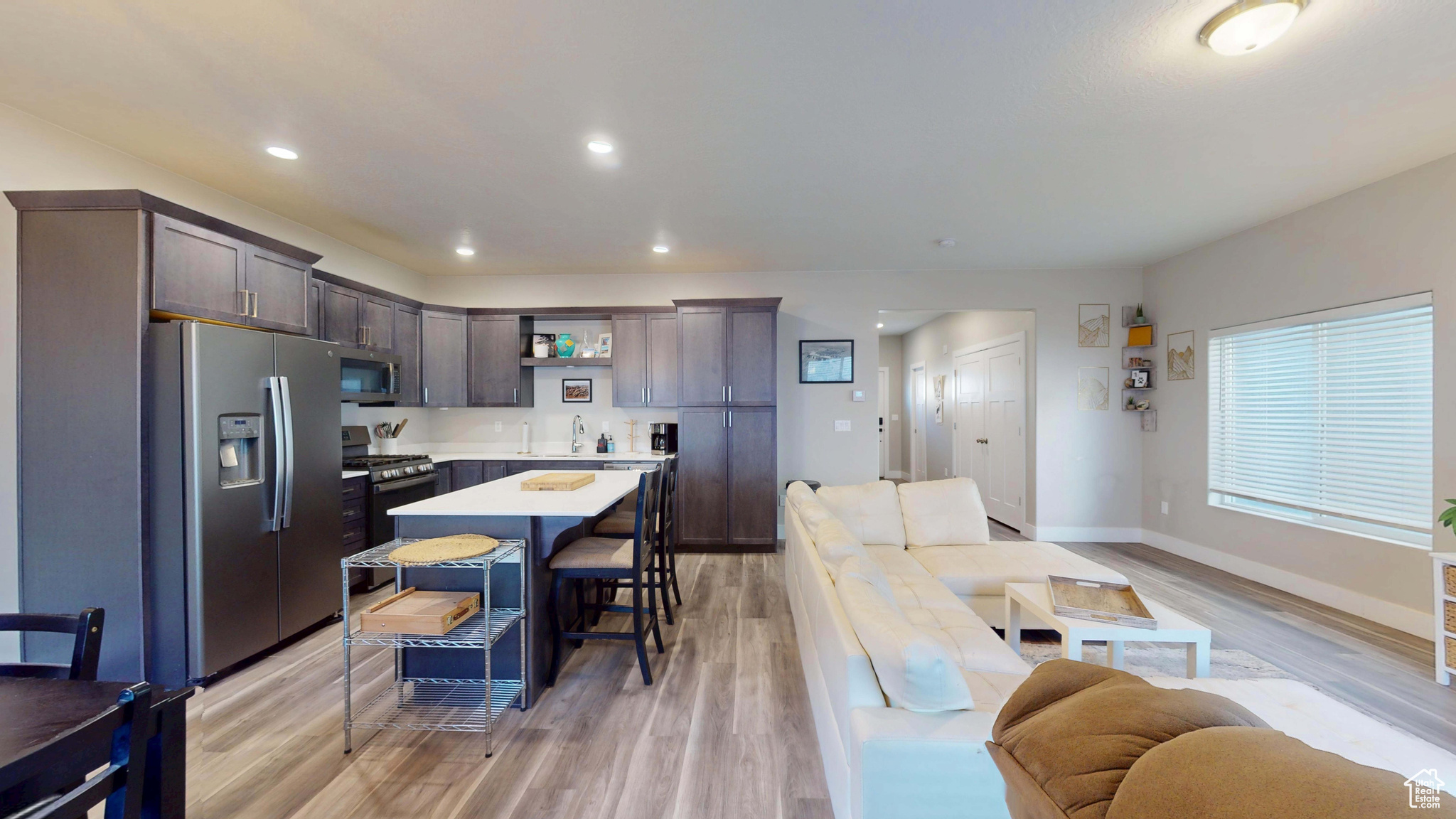 Kitchen featuring appliances with stainless steel finishes, a breakfast bar area, a center island, light hardwood / wood-style floors, and dark brown cabinets