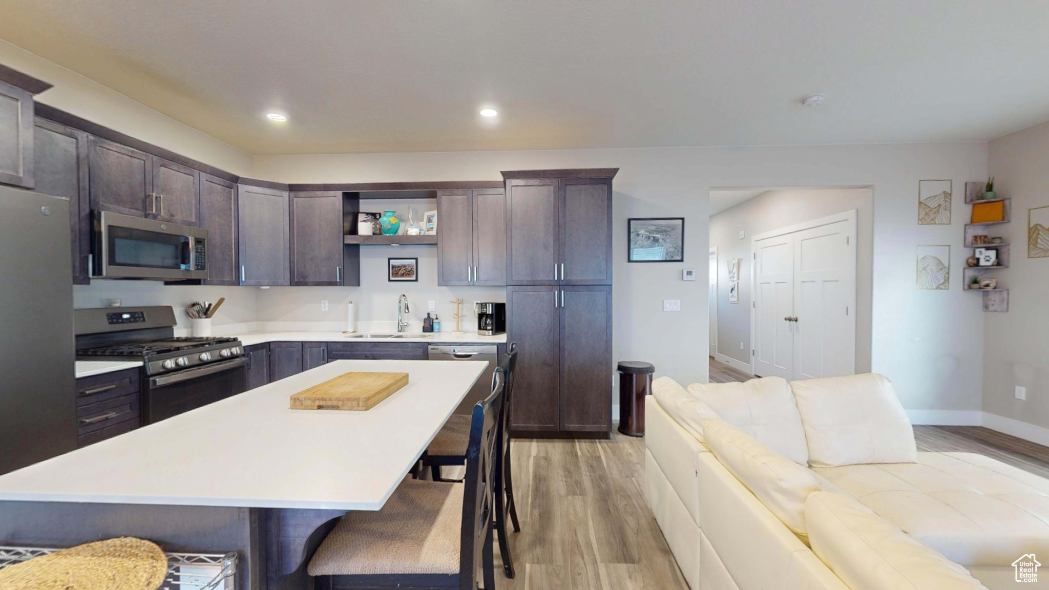 Kitchen featuring dark brown cabinetry, a kitchen bar, a kitchen island, stainless steel appliances, and light hardwood / wood-style floors