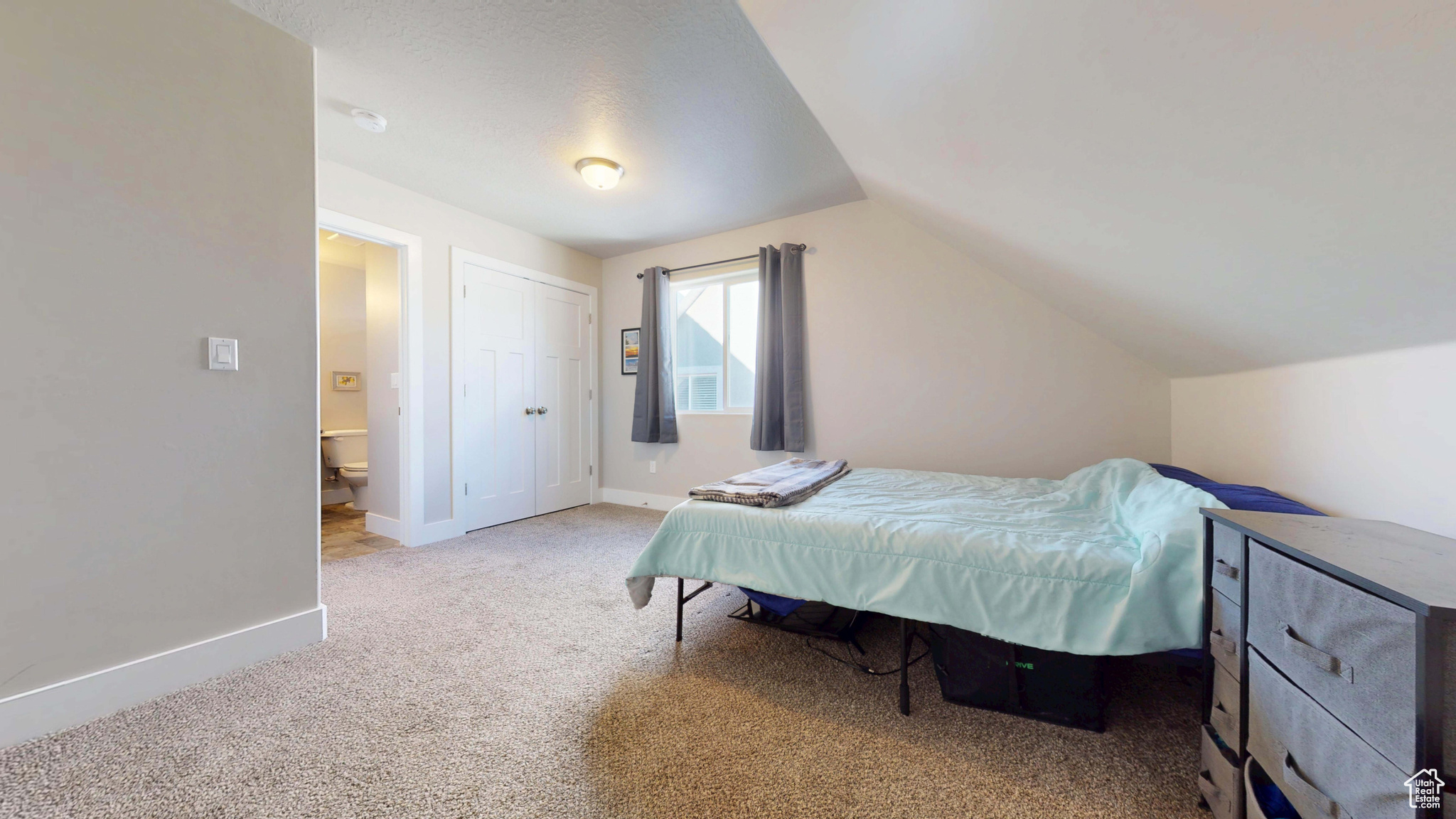 Carpeted bedroom featuring lofted ceiling and a closet