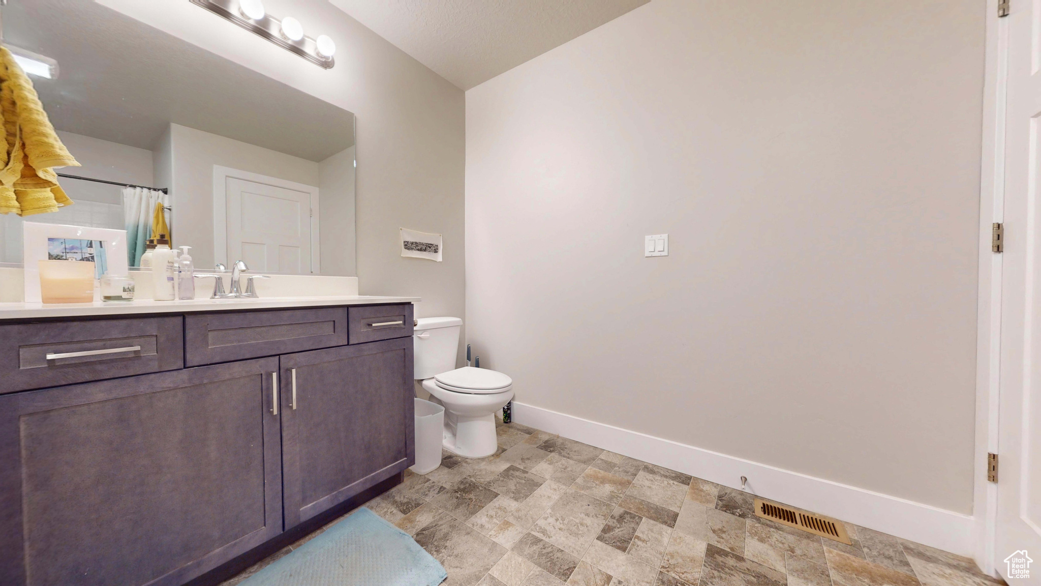 Bathroom featuring a shower with curtain, vanity, and toilet