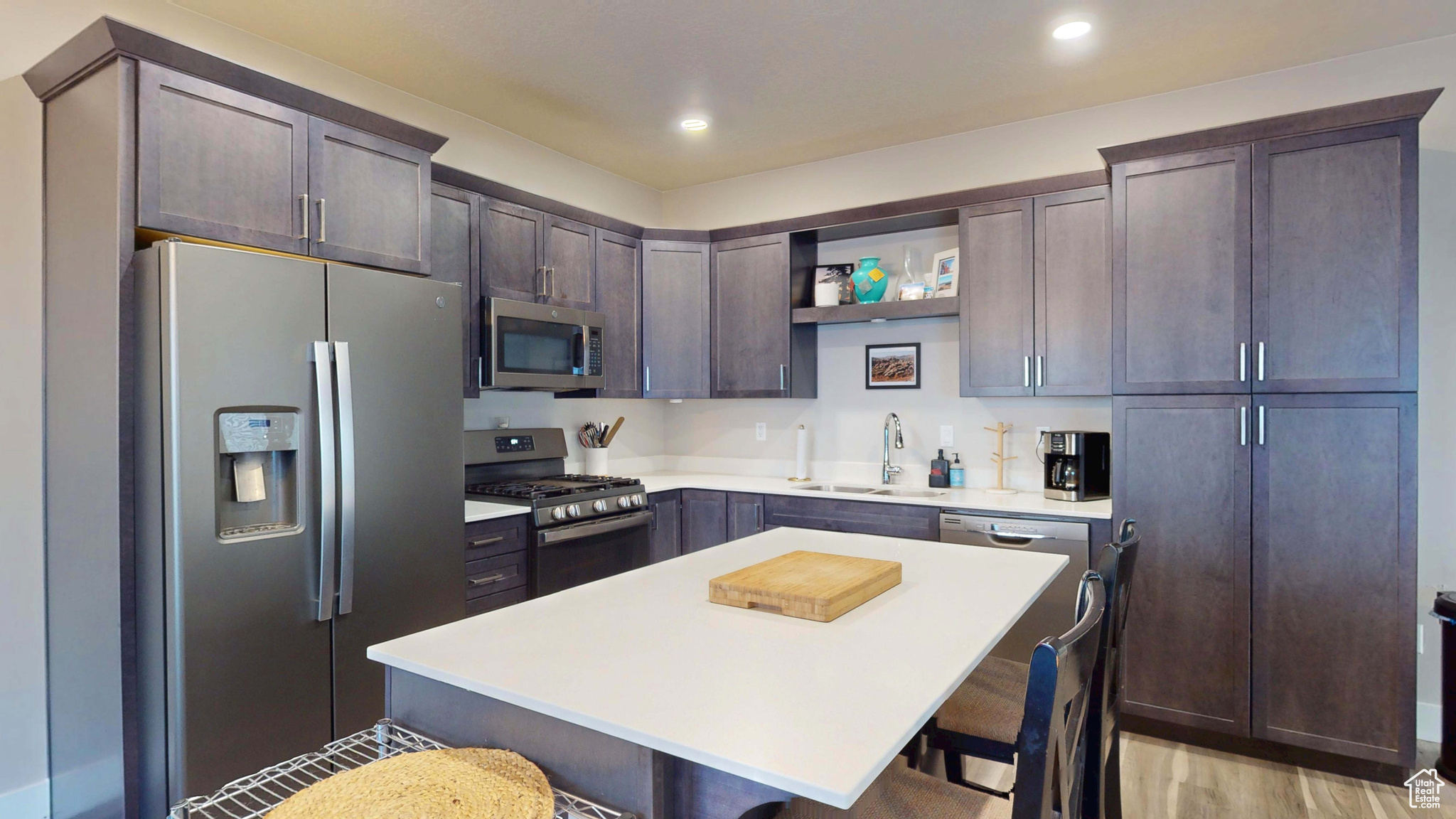 Kitchen with a kitchen island, sink, a kitchen bar, dark brown cabinetry, and stainless steel appliances